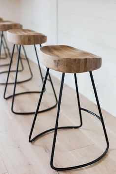 three stools sitting on top of a hard wood floor next to a white wall