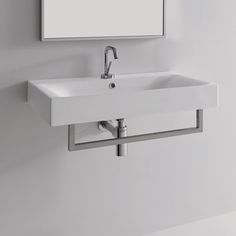 a white bathroom sink sitting under a mirror next to a wall mounted faucet