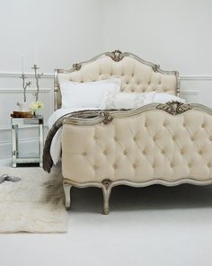 a white bed sitting next to a rug on top of a floor