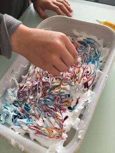 a person is making something out of shredded paper in a container on a table with other items