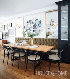 a dining room table with chairs around it and plates on the wall in the background