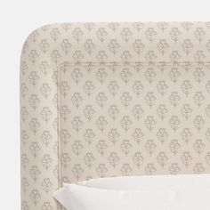 an upholstered headboard with a white pillow and decorative wallpaper on it