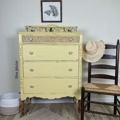 a yellow dresser sitting next to a wooden chair in a room with white walls and wood floors