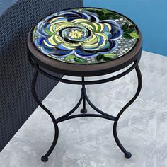 a small table with a flower design on it sitting in front of a blue wall