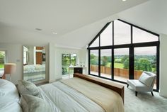 a bedroom with large windows and white furniture