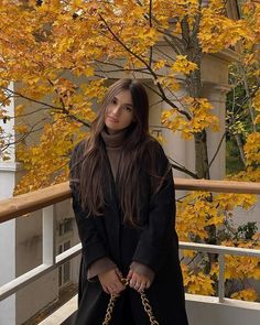 a woman is standing on a balcony with her hand in her pocket and holding onto a chain