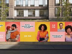 a large advertisement on the side of a building with people smiling and standing in front of it