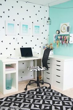 a white desk topped with a laptop computer next to a wall covered in black and white triangles