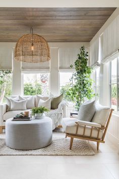 a living room with white furniture and plants on the windows sill, along with a round coffee table