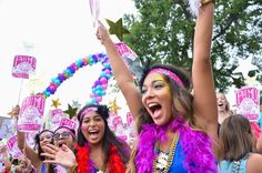 a group of women in colorful costumes holding up their hands and posing for the camera