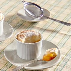 two plates with desserts on them and spoons next to one plate that is half eaten