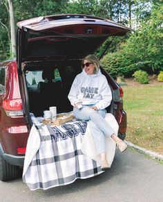 a woman sitting in the back of a car with a picnic blanket on her lap