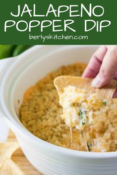 someone dipping cheese into a bowl of jalapeno popper dip