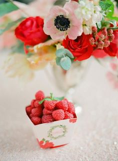 raspberries and flowers in a vase on a table