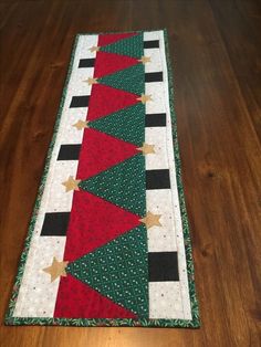 a christmas table runner with red, green and gold stars on it sitting on a wooden floor