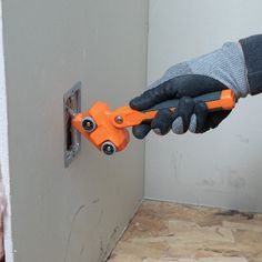 a person wearing gloves and holding a pair of scissors in front of a gray wall