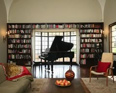 a living room filled with furniture and a piano in front of a book shelf full of books