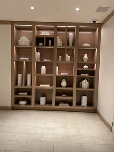 an empty room with shelves and vases on the wall in it's center