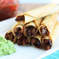 three burritos on a plate with guacamole