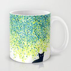 a coffee mug with a black cat sitting under a tree filled with green and blue leaves