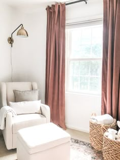 a living room filled with furniture and a window covered in pink drapes next to a white chair