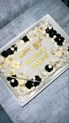 a birthday cake with white frosting and black flowers on the top is sitting on a table