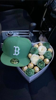 a baseball cap and some roses in a heart shaped box on a car dash board