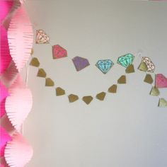 the wall is decorated with different colored paper hearts and diamond shaped garlands on it