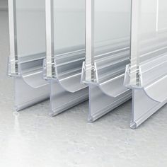 three clear acrylic shelves are lined up against each other on the floor in an empty room