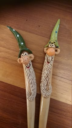 two toothbrushes with gnome heads on them sitting on a wooden table next to each other