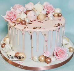 there is a white cake with pink and gold decorations on the top, decorated with flowers