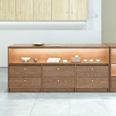 a large wooden cabinet with drawers and plates on the top, in an empty room