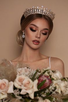 a woman wearing a tiara with flowers in front of her and holding a bouquet