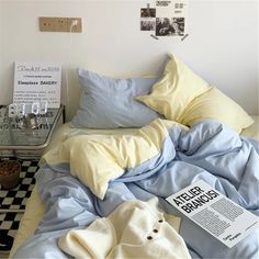 an unmade bed with blue sheets and yellow pillows on top of it next to a black and white checkered floor