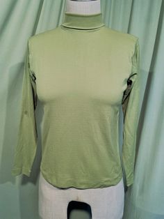 This is a sweet, vintage top from the 70s. No labels.  No size tag. The bust measures 34" without stretching, see measurements below.   Made of a bright olive green polyester, a bit brighter than the photos show.  The top has a folded turtleneck neckline that is stitched in the folded position & zips in the back with a nylon zipper. It has long sleeves. The top is in good condition!  Minimal wear.  No soil or stains.  Classic!  Measurements were taken with the garment lying flat. If you have never worn vintage before, please measure yourself!! Vintage sizes run smaller than today's sizes, know your measurements before buying! Bust measured from side seam to side seam at the underarm: 17" unstretched for a 34" or slightly smaller or larger bust Waist from side seam to side seam at the hemli Vintage Green Tops For Fall, Retro Stretch Long Sleeve Tops, Fitted Vintage Crew Neck Top, Fitted Cotton Turtleneck Top, Retro Solid Tops For Fall, Retro Green Tops For Fall, Solid Retro Tops For Fall, Classic Green Stretch Top, Green Stretch Classic Top