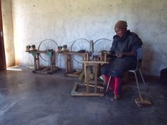 a woman sitting at a table working on spinning wheels