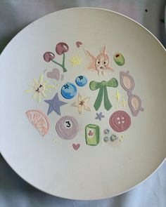 a white plate with some drawings on the side and other things drawn on it to look like they are made out of clay