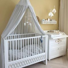 a white crib in a yellow room with curtains on the top and bottom half