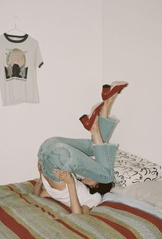 a woman laying on top of a bed next to a t - shirt and shoes