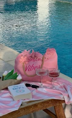 a towel, wine glass and book on a table near a pool