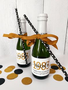 two champagne bottles with gold confetti tied to them and black polka dots on the table