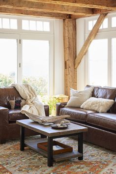 a living room with leather furniture and large windows in the background, including a coffee table