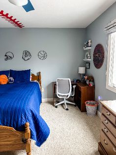 a bedroom with a bed, desk and basketball on the wall