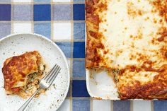 a white plate topped with lasagna next to a casserole dish on a blue and white checkered table cloth