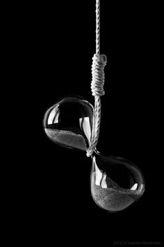 two sandglass hanging from a rope on a black background