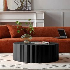 a living room with an orange couch, coffee table and laptop computer on the floor