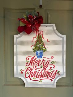 a merry christmas sign hanging from the side of a door with a bow on it