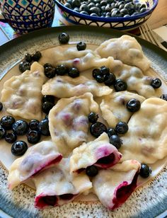 blueberries and cream cheese ravioli on a plate next to bowls of olives