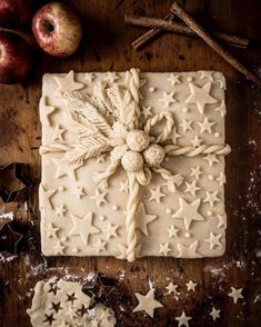 an apple and star shaped cookie on a wooden table with cinnamon sticks, apples and other decorations