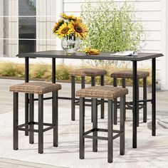 a table with four stools and a vase full of sunflowers